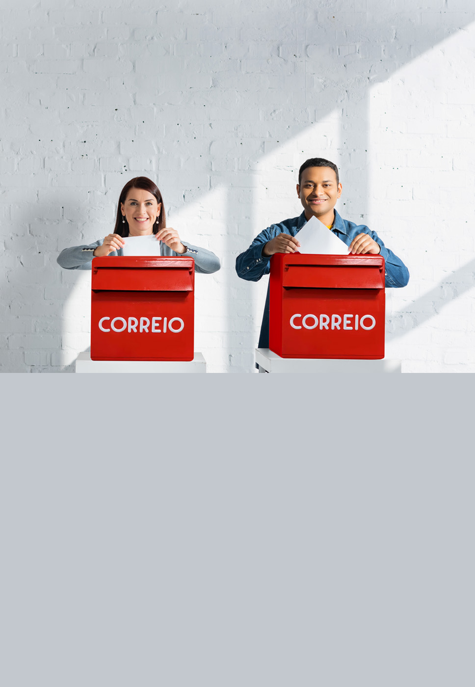 Duas pessoas a colocarem correio em duas caixas de correio vermelhas